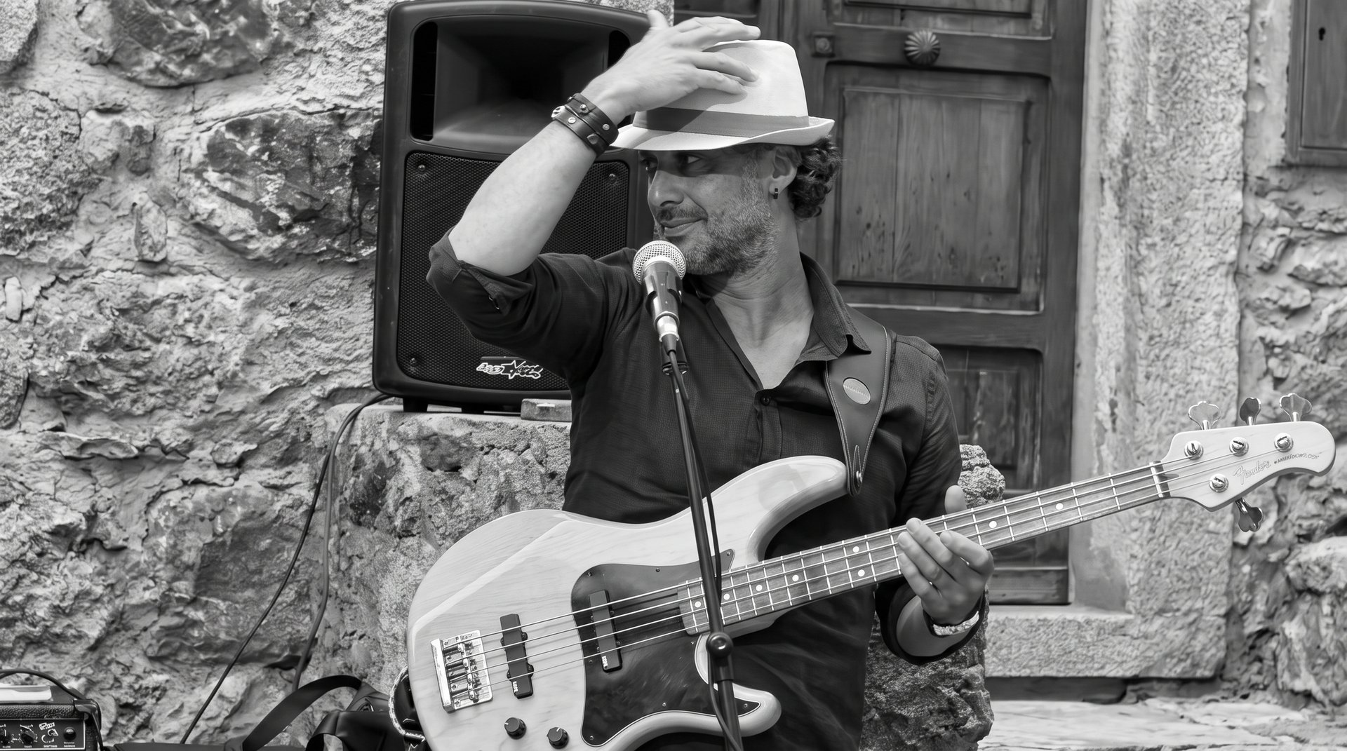 Osman Meyredi with his bass at an outdoor show in Italy, black and white
