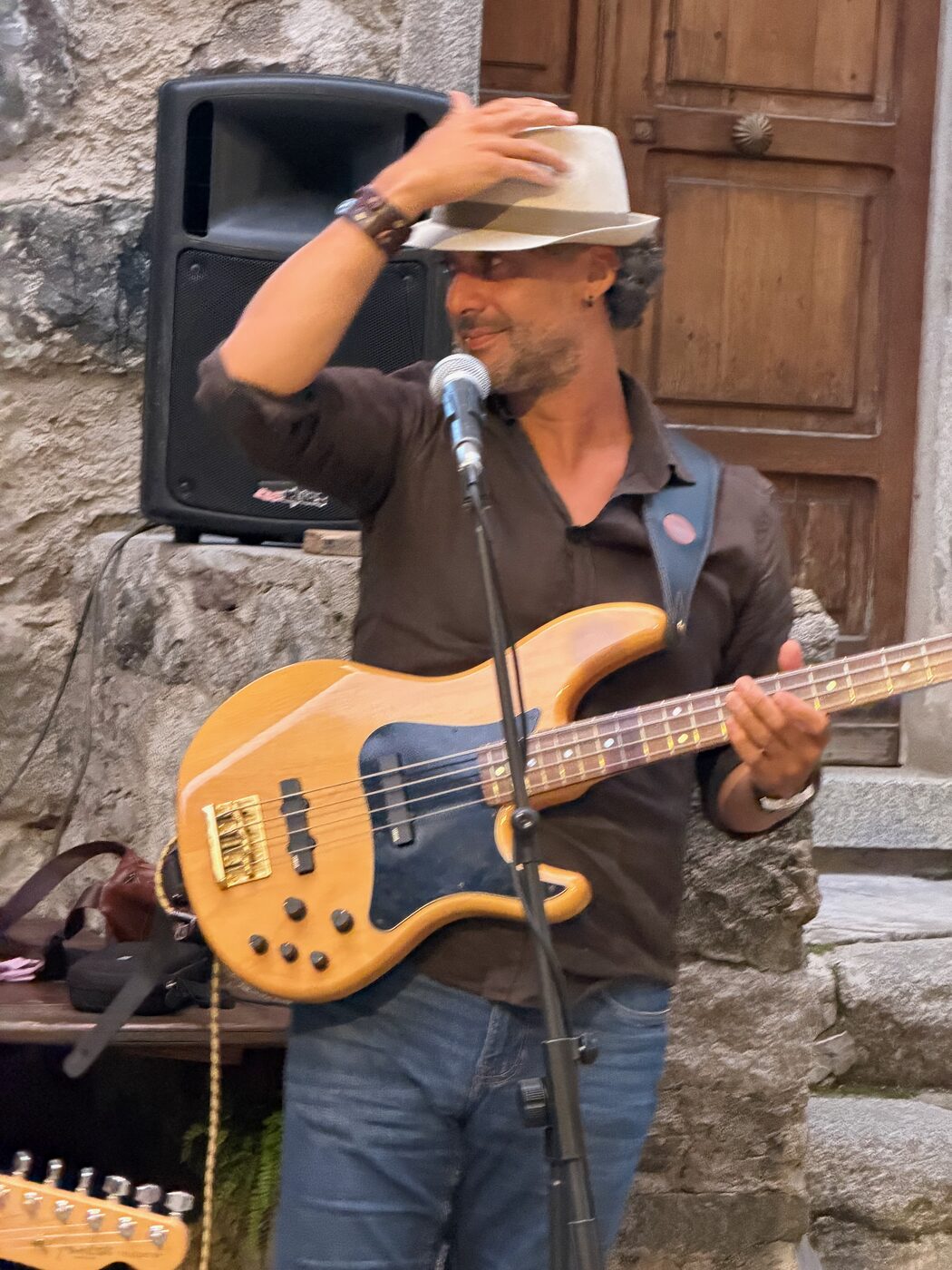 Osman Meyredi with his bass by an old doorway, tipping his hat