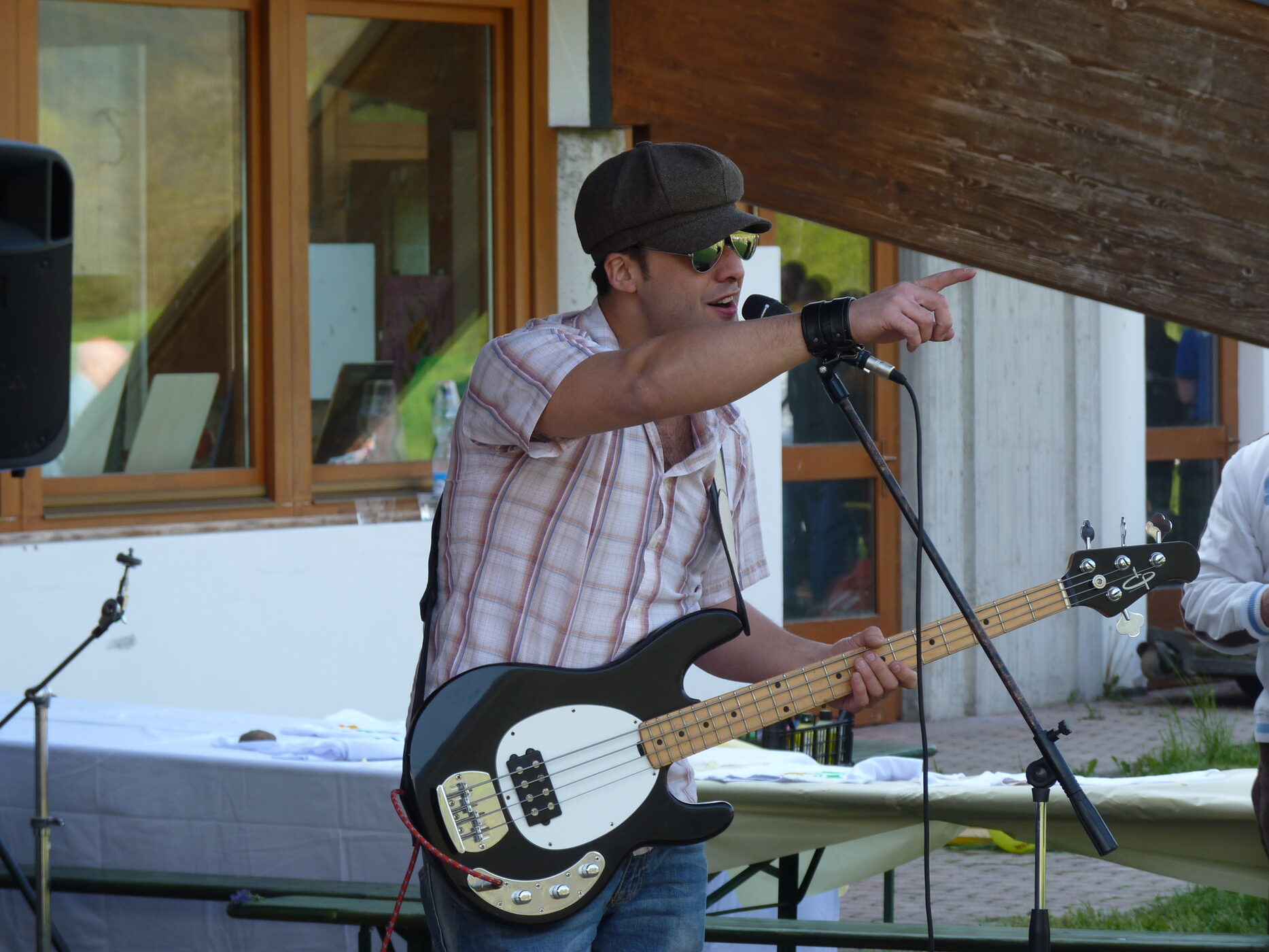Osman Meyredi pointing to the crowd, bass guitar in hand, at an outdoor show in Italy