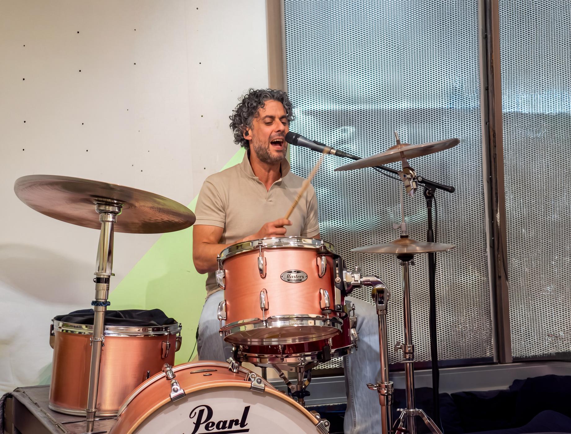 Osman Meyredi singing behind a drum kit