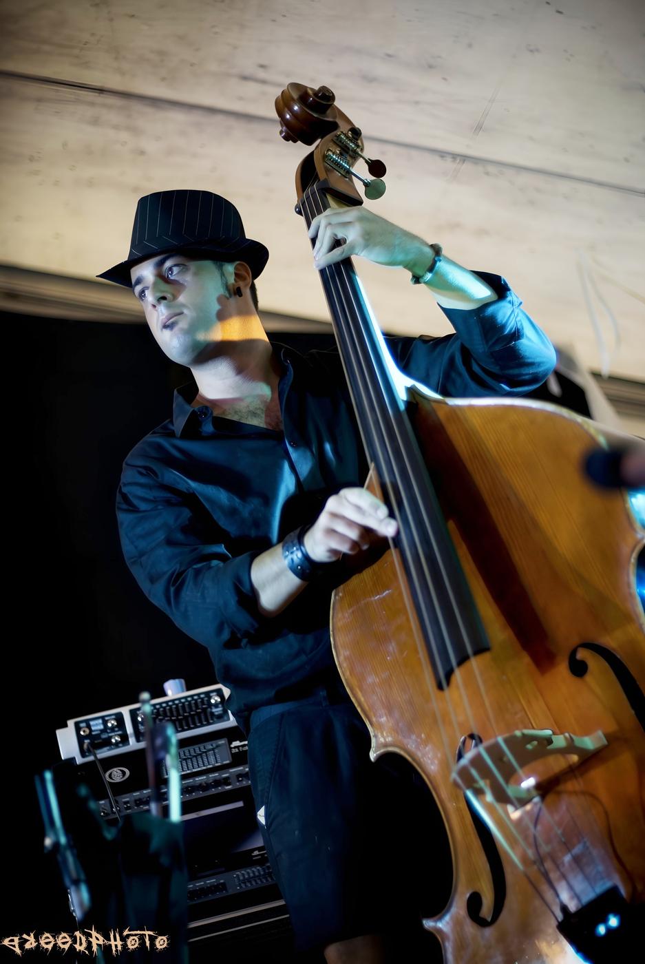 Osman Meyredi in a hat playing the double bass on stage, blue light