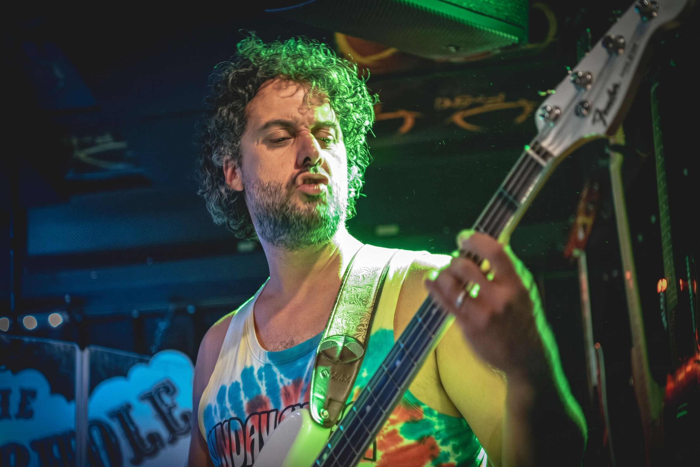 Osman Meyredi playing bass guitar under green stage light
