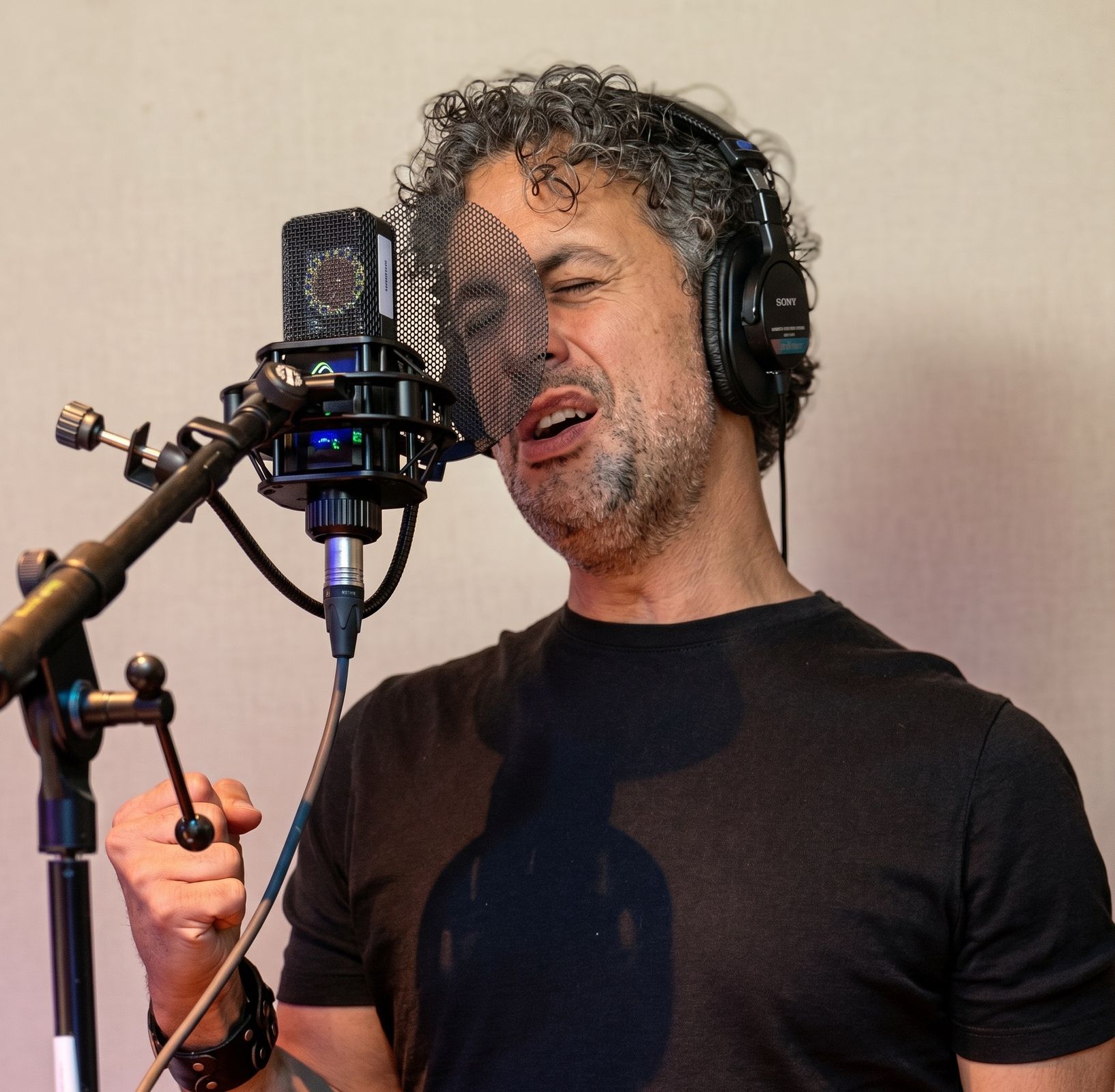 Osman Meyredi singing into a studio microphone, headphones on